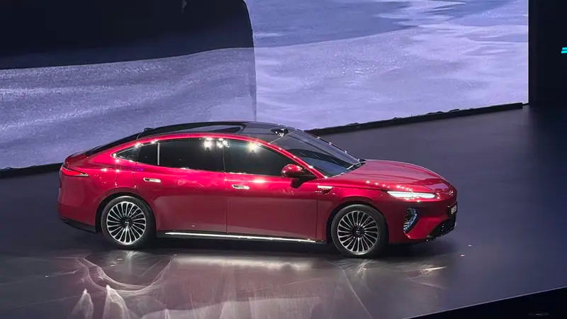 Carro elétrico vermelho em evento, destacando design moderno e tecnologia avançada em um palco iluminado.